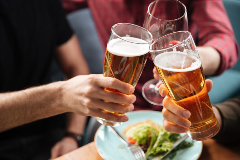 Young friends sitting in cafe while drinking alcohol