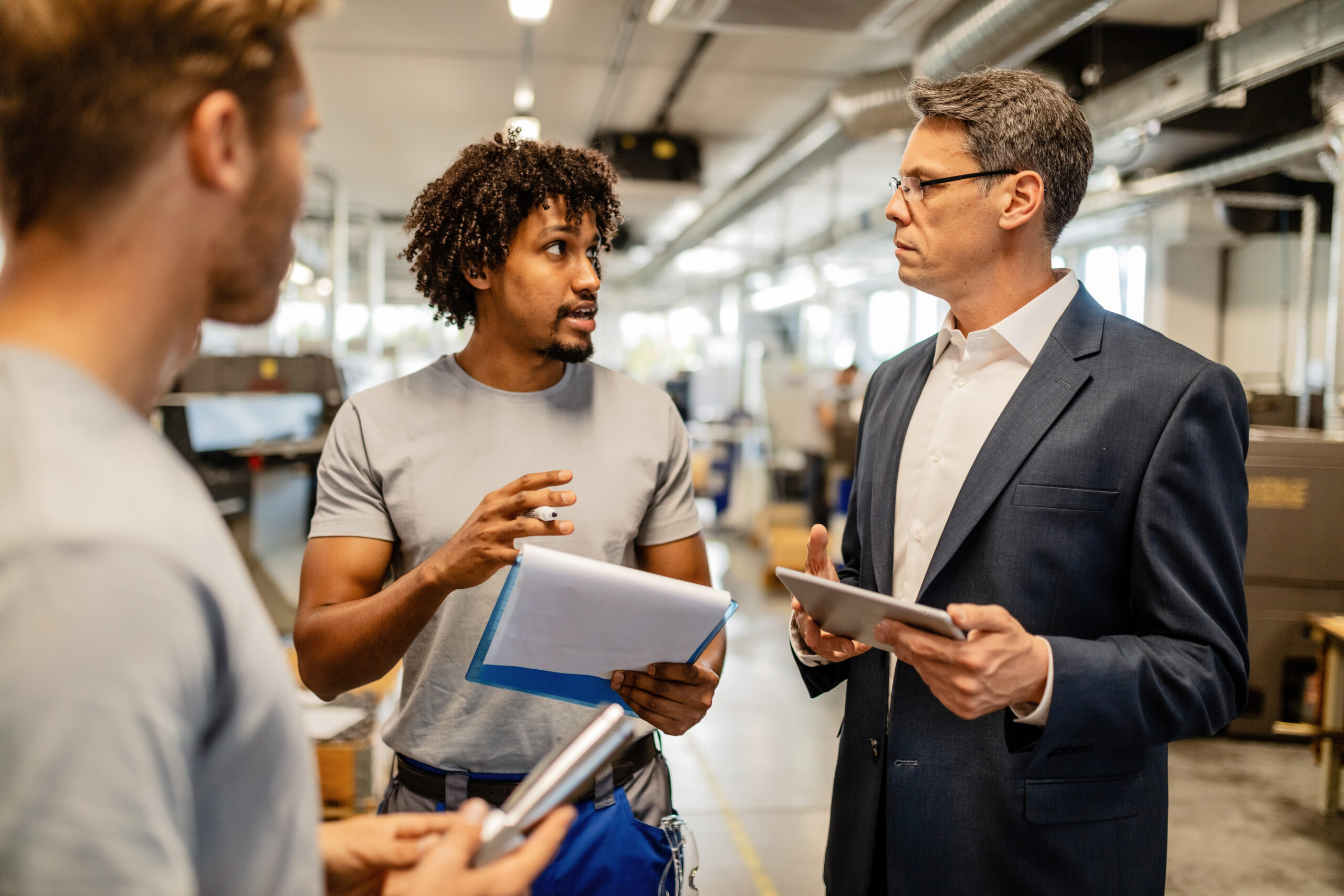 African American worker talking with a manager while going through reports in steel factory